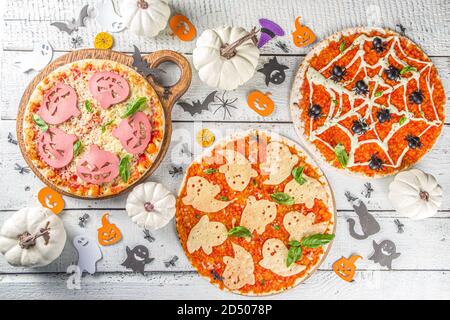 Verschiedene Halloween lustige Pizza. Halloween Party Rezept, Kreative Idee für Halloween Pizza`s mit Schinken und Käse Geister, Monster, Spinnen, weiß Holz Stockfoto